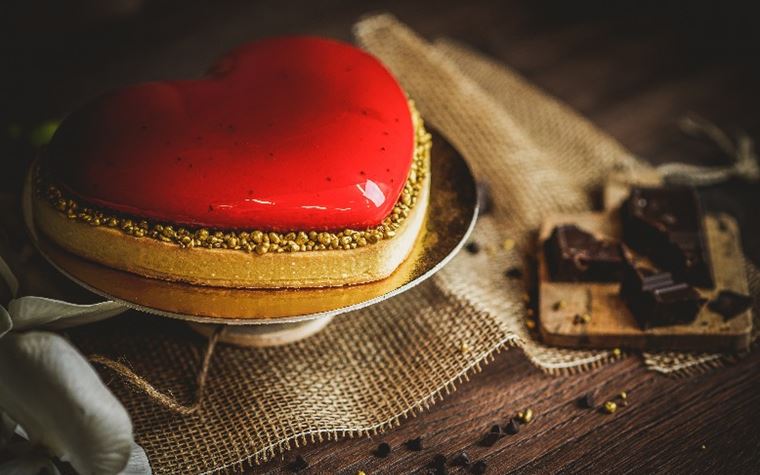 Crostata moderna a forma di cuore con crema al cioccolato e mousse al lampone glassata di rosso a specchio 